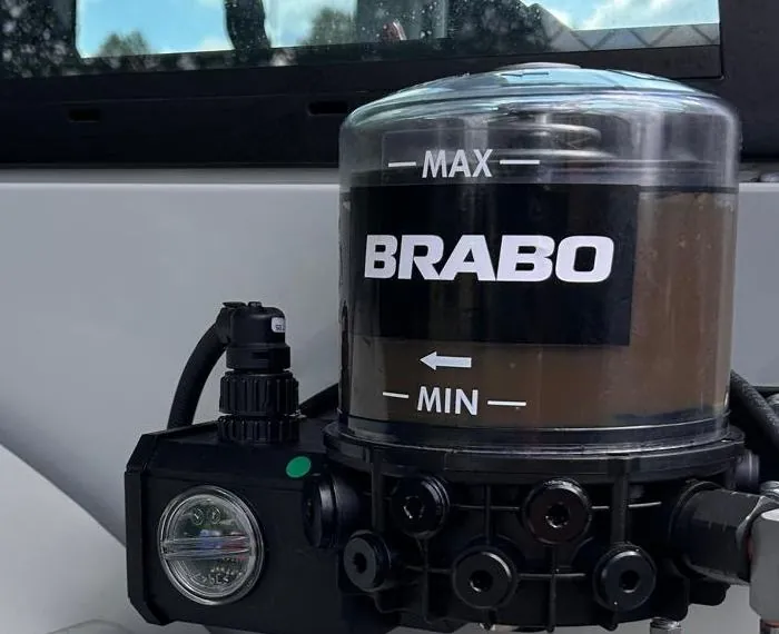 Close-up van een BRABO smeerpomp met transparant vetreservoir en MAX/MIN-markering