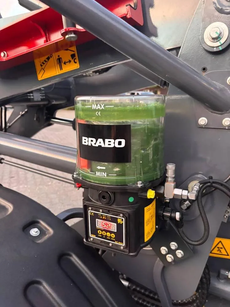 BRABO smeerpomp met vetreservoir en digitaal display gemonteerd bij de giek van een wiellader