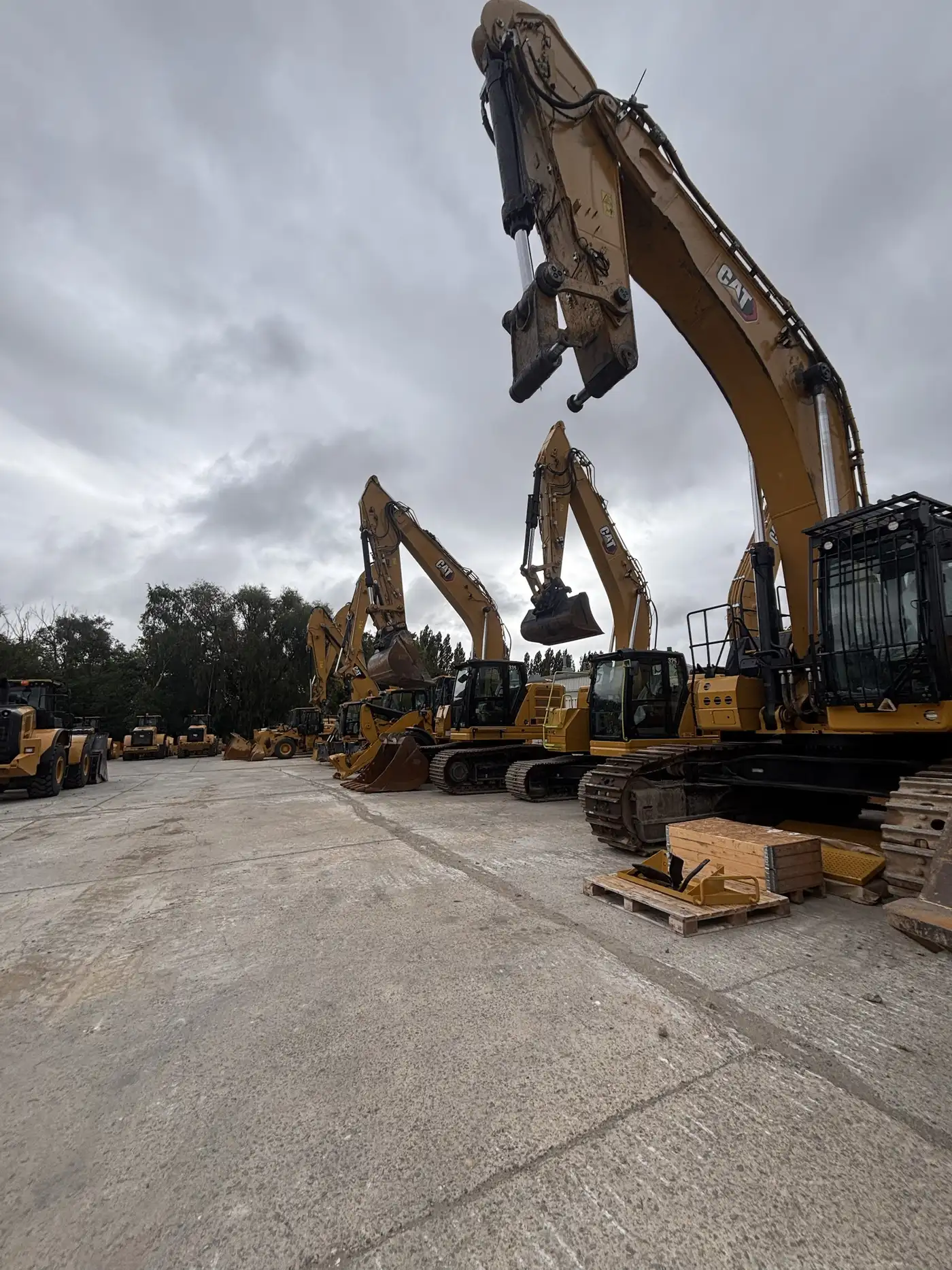 Rij gele Cat-graafmachines en wielladers op het bedrijfsterrein van een dealer