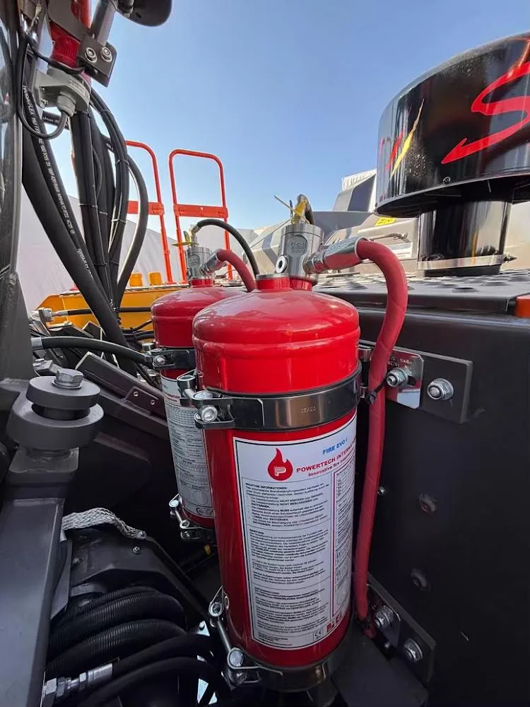 Twee Powertech-blusflessen van een automatisch blussysteem, gemonteerd naast de motorruimte van een machine